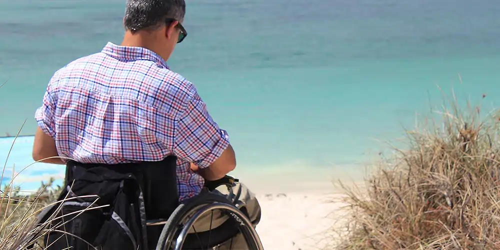 Mann im Rollstuhl am Strand der Ostseeküste in Mecklenburg-Vorpommern